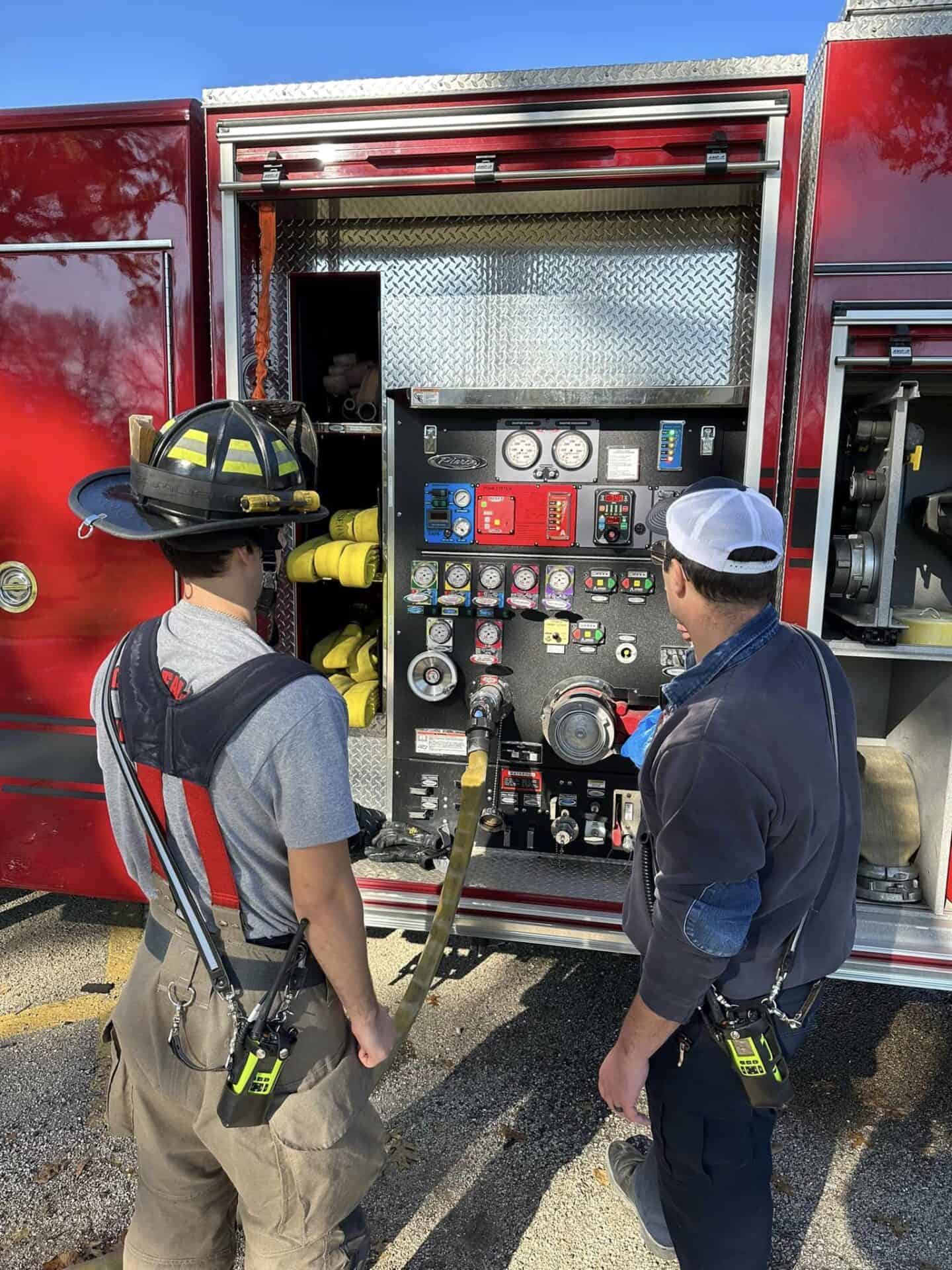 Firefighters inspecting equipment on a fire truck.