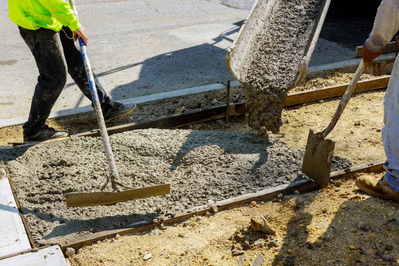 Construction workers pouring and leveling fresh concrete.