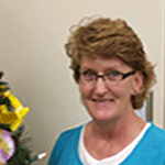 Smiling woman in a blue shirt near decorations.